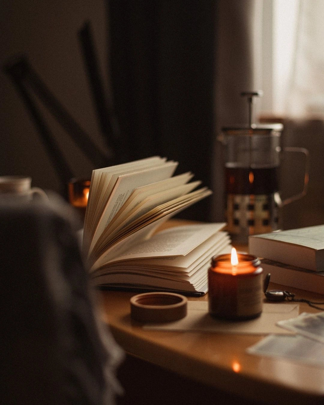 Candle and open book on a wooden table, seasonal self-care ritual